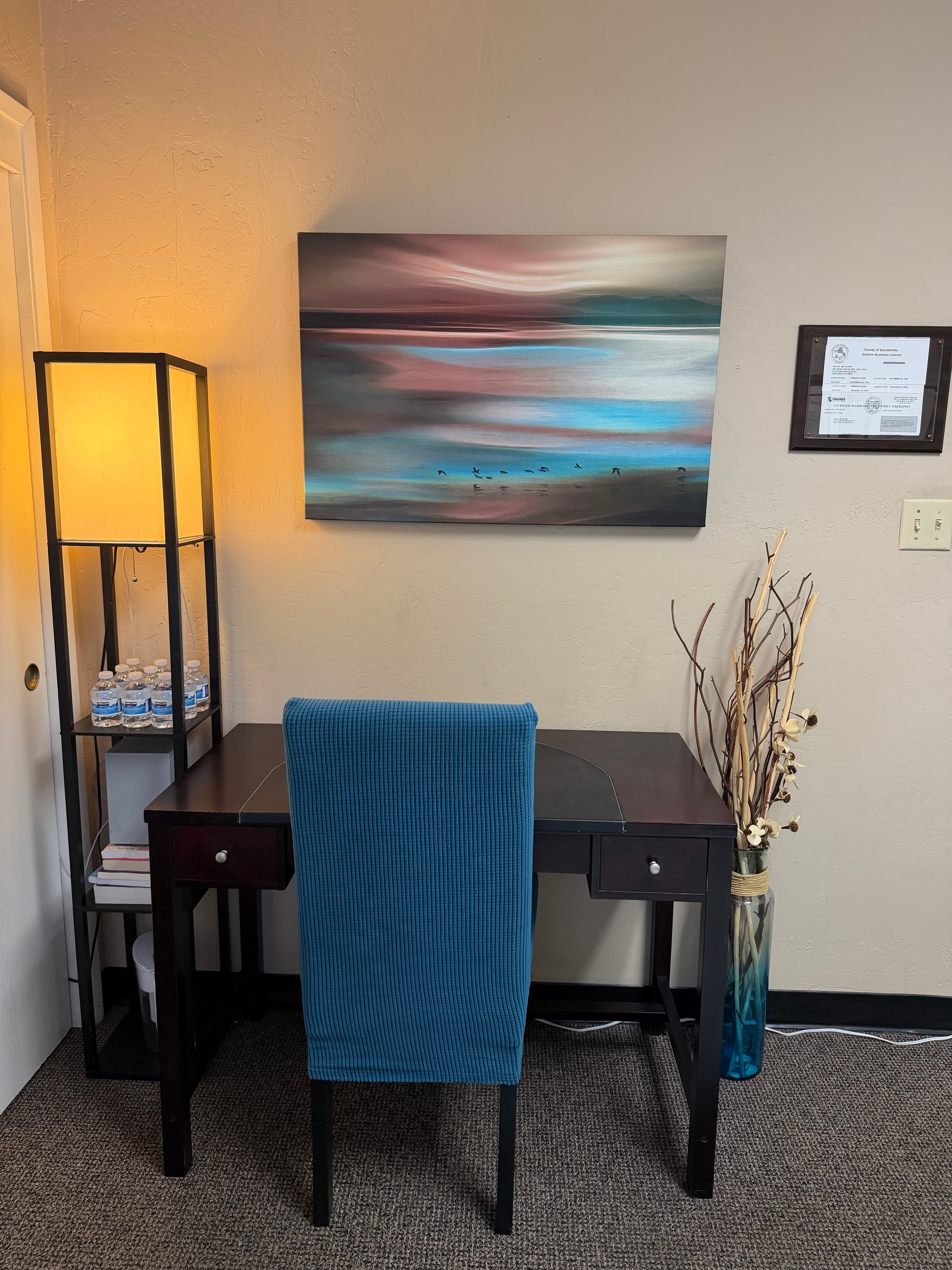Therapy office desk area with coastal artwork